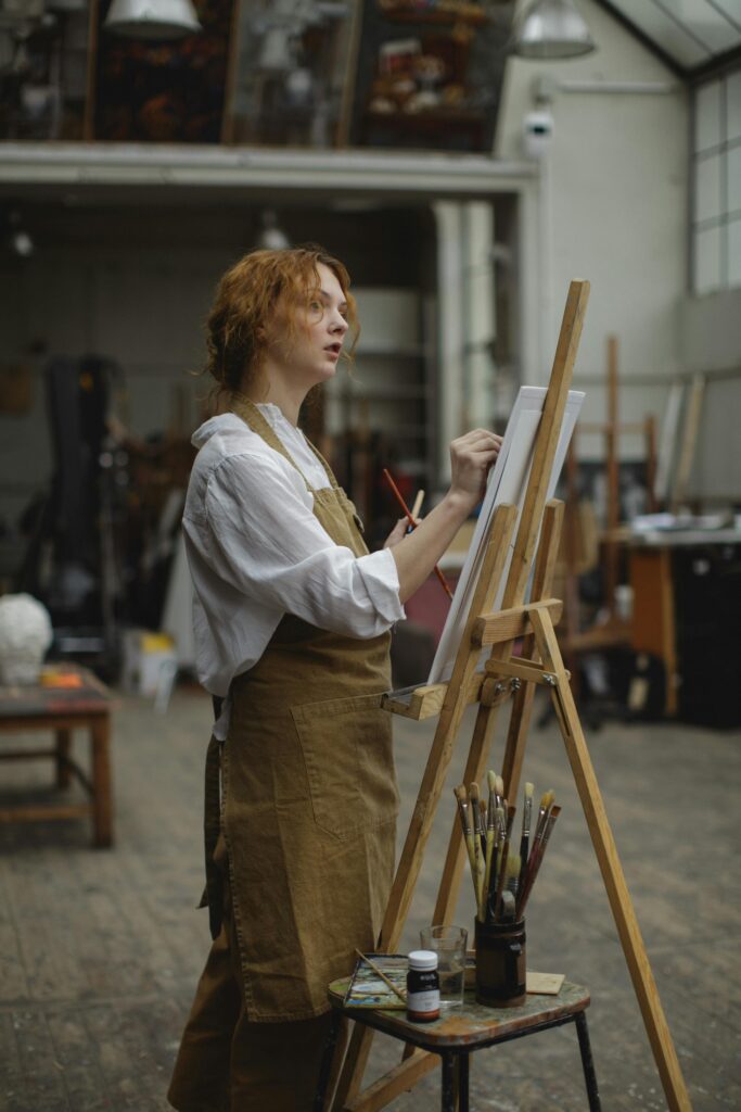 A girl sitting and drawing on a canvas with focus and creativity.